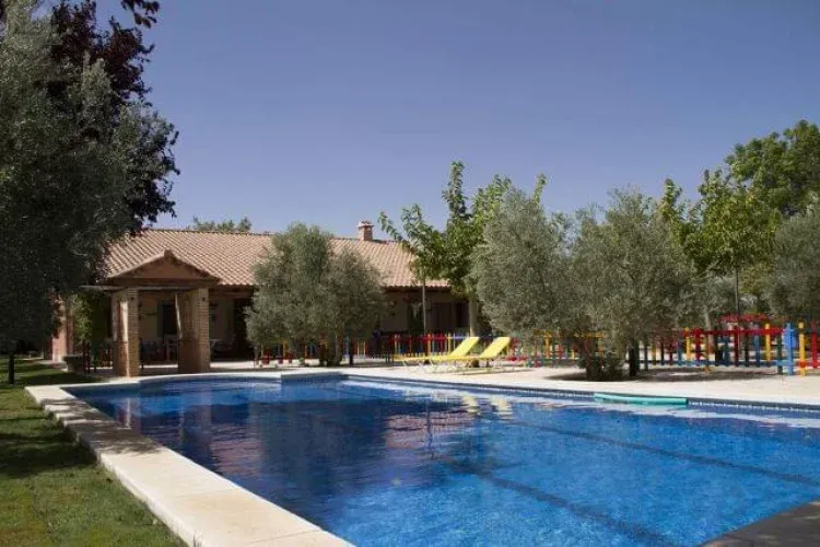 La piscina de Días de Campo rodeada de olivos, con la casa al fondo